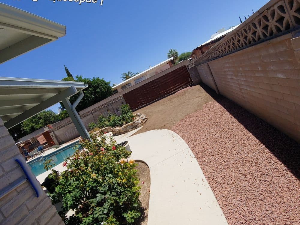 Backyard with pool, garden, and gravel area under clear blue sky. Ideal for outdoor relaxation.