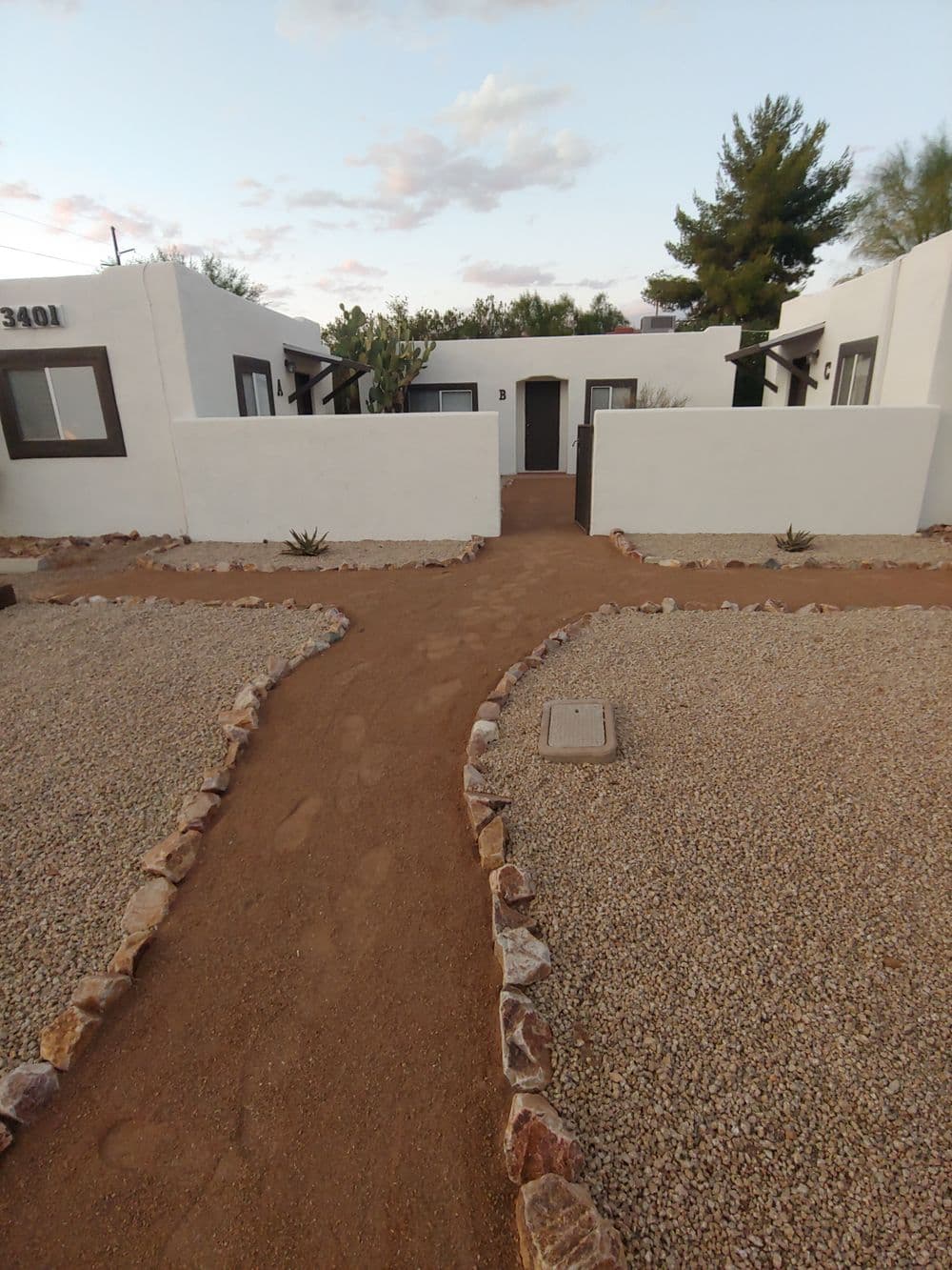 Desert-style white bungalow complex with gravel pathways and cacti landscaping.