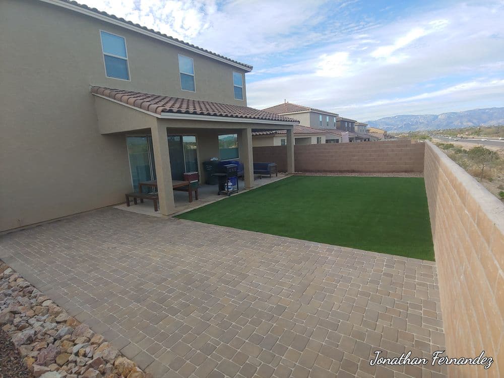 Backyard view featuring artificial grass, patio, and stone pathway against a mountain backdrop.