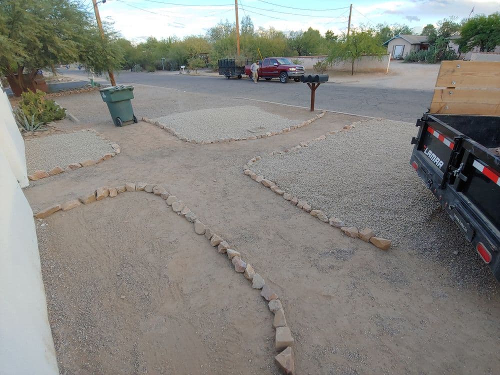 Gravel landscaping with stone borders in a residential area, showcasing a truck and street view.