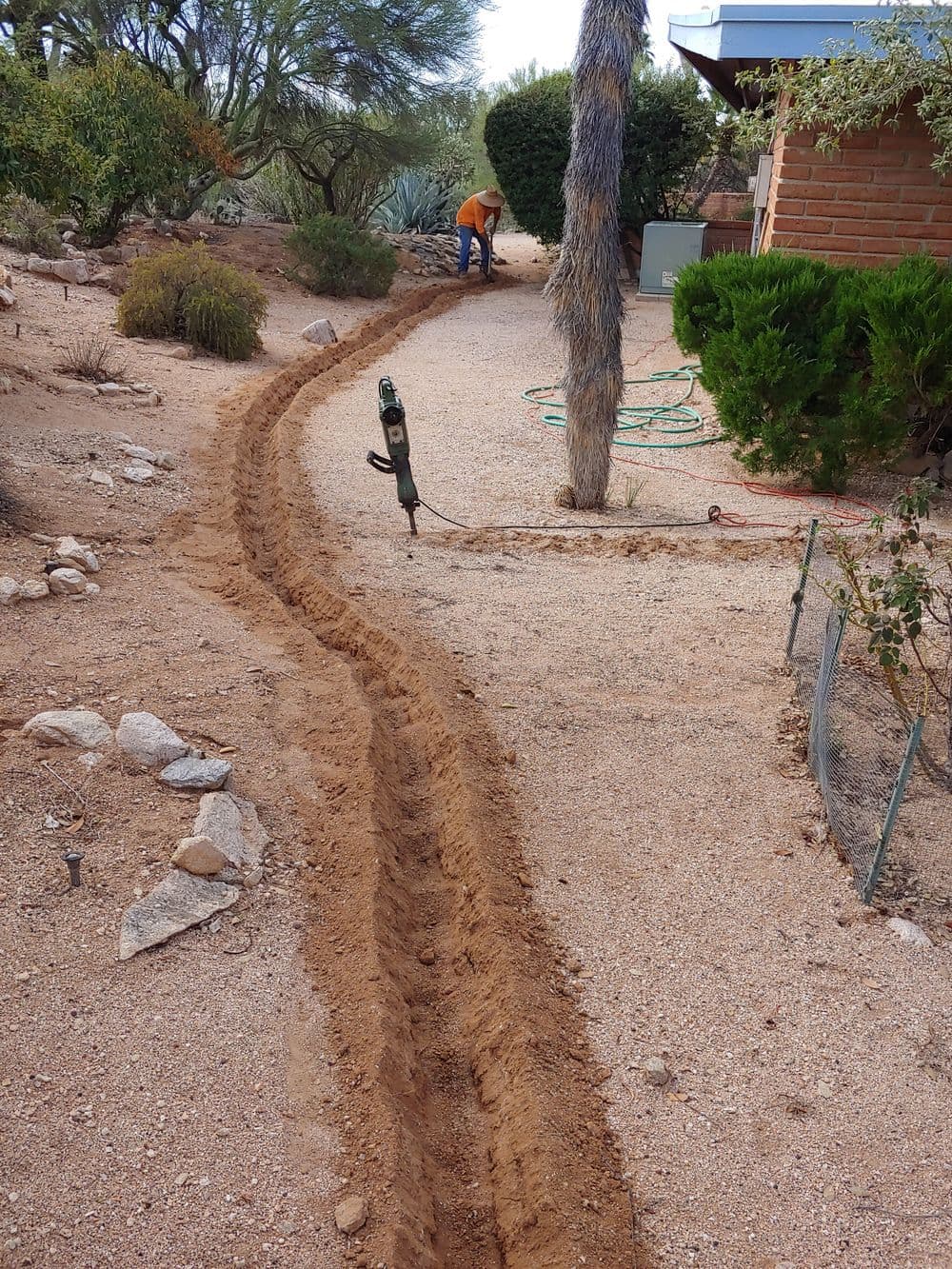 Garden pathway being created in a desert landscape, with a person working in the background.