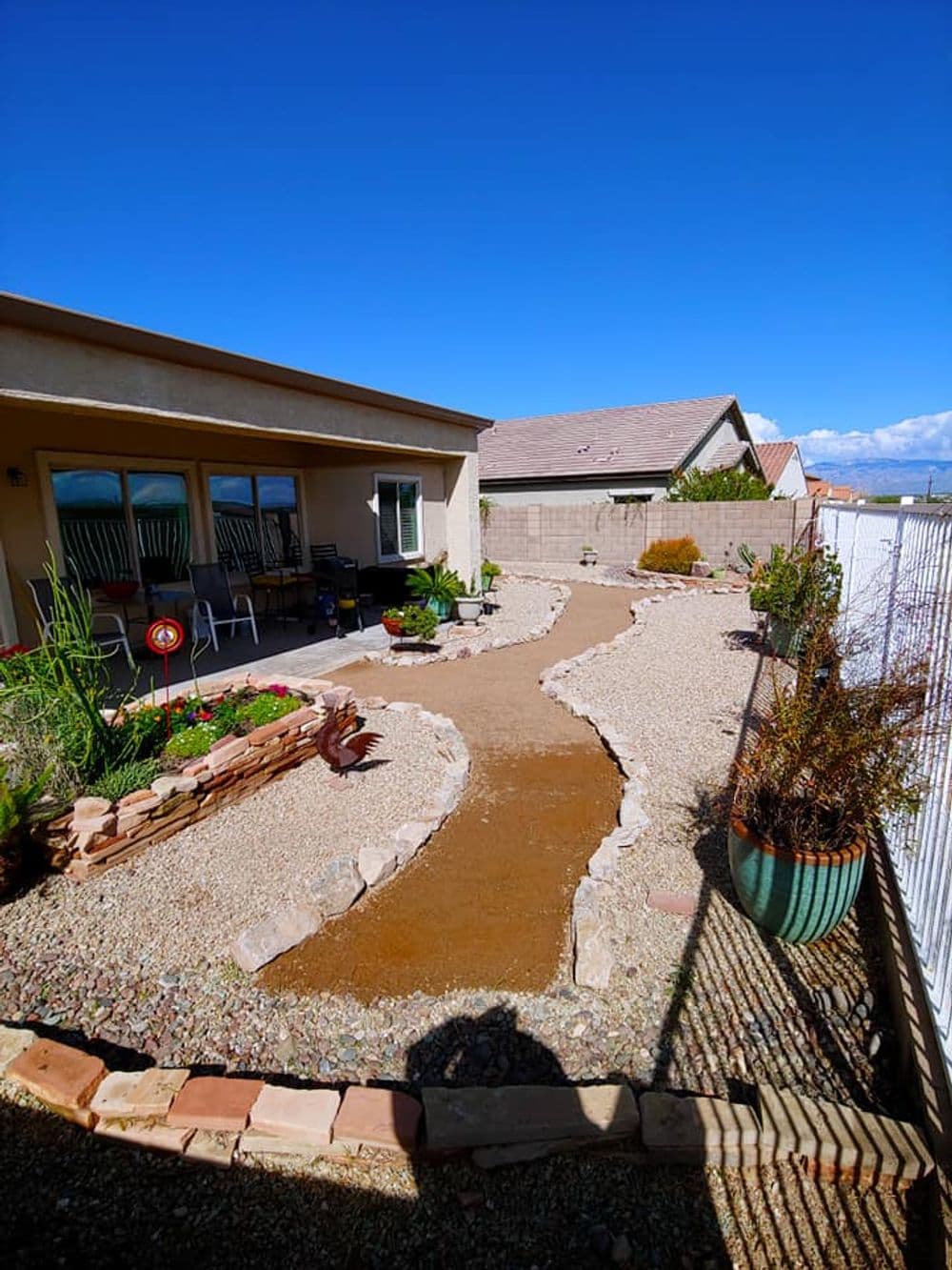 Desert landscape design featuring a winding gravel path beside a home and garden.